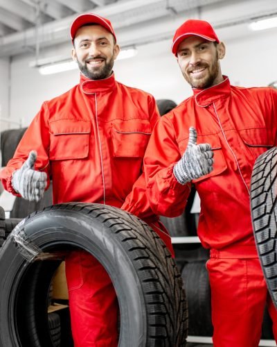 Workers with car tires at the warehouse Portrait of a two workers in red uniform with car tires at the warehouse of the car service
